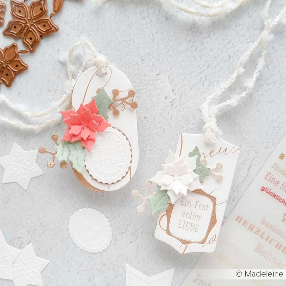 Zwei handgefertigte weihnachtliche Geschenkanhänger von Alexandra Renke mit Weihnachtssternen, Stechpalmenblättern und weihnachtlichen Botschaften, gefertigt mit der Motivstanze aus unserer weihnachtlichen Blumensammlung.