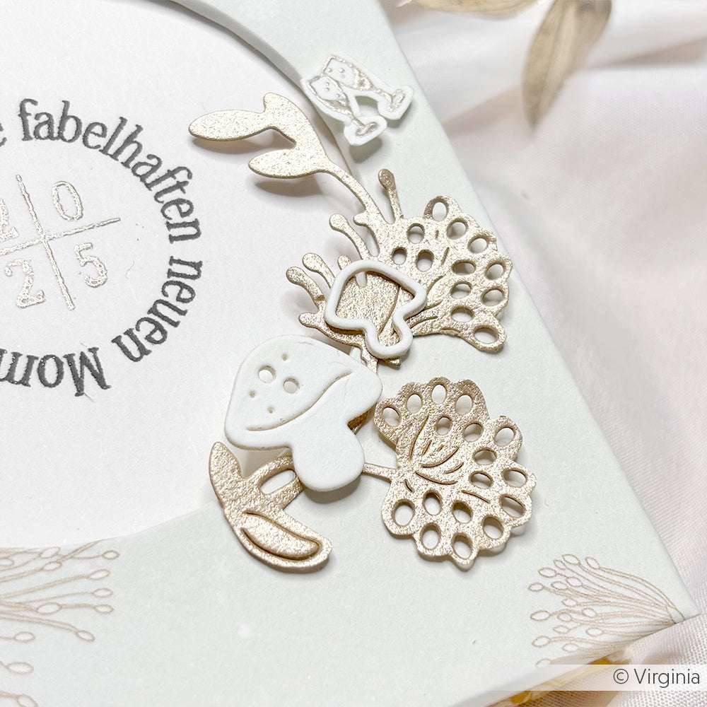 Weiße und glitzernde gestanzte Pilze und Blätter, die mit der Alexandra Renke Motivstanze Pilz Trio hergestellt wurden, schmücken eine Karte mit deutschem Text und zarten Goldakzenten.