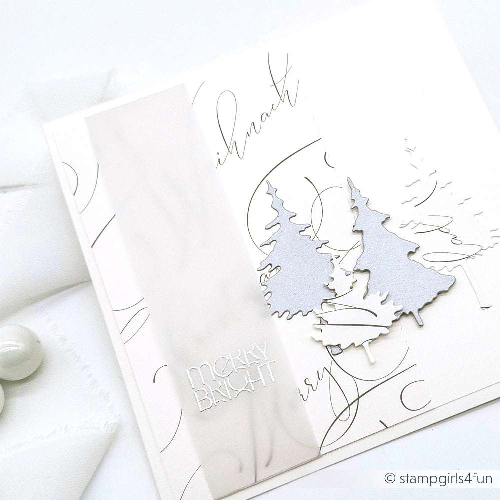 Elegante weiße Weihnachtskarte von Alexandra Renke mit silbernen Bäumen, die mit der Motivstanze Tannen Trio gestaltet wurden, einem Pergamentstreifen und dem Text Merry Bright vor einem Hintergrund in Schreibschrift.