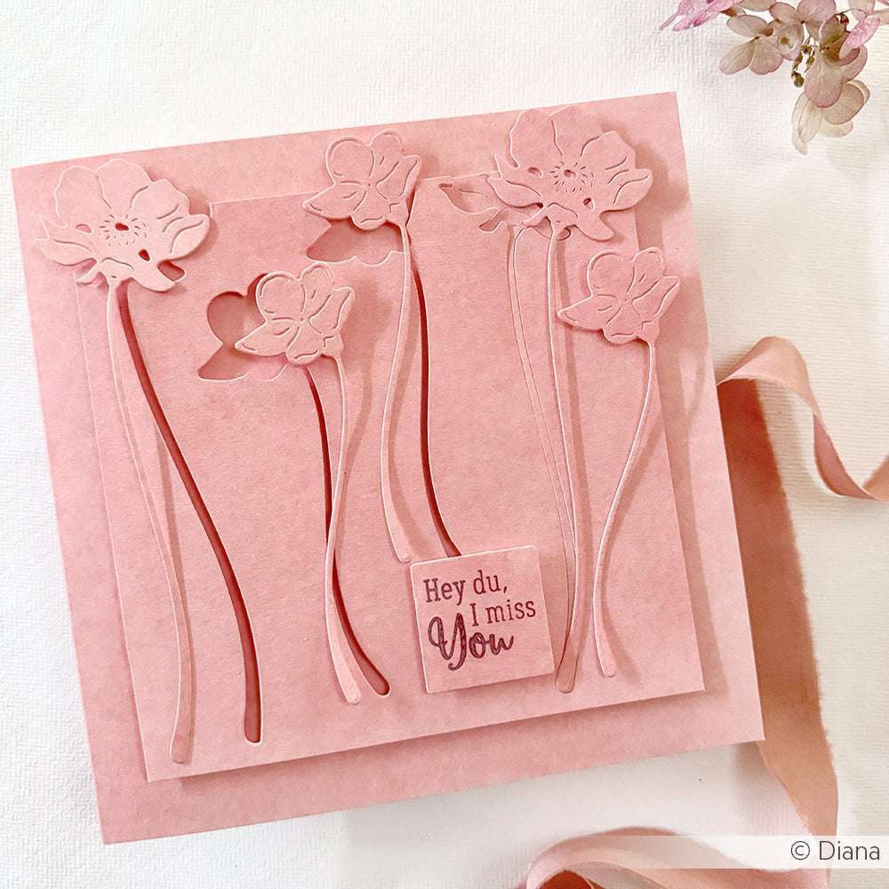 Rosa Blumengrußkarte von Alexandra Renke mit gestanzten Blumen, einem Herz und "Hey du, ich vermisse dich" auf der Vorderseite, hergestellt mit Deep Edge Motivstanzen und PAPPcut®ies.