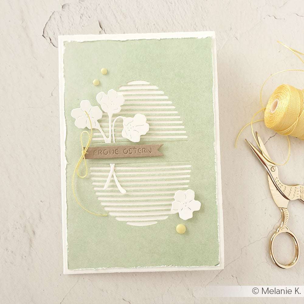 Handgemachte Osterkarte von Alexandra Renke mit weißen Blumen, gelbem Faden und "Frohe Ostern" auf grünem Hintergrund, hergestellt mit der Motivstanze Feines Blüten Duo für feine florale Akzente.