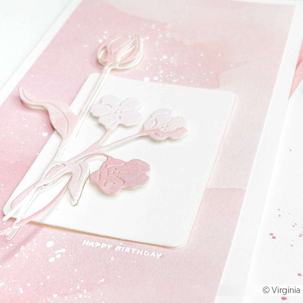 Eine Geburtstagskarte mit Blumen in Pastellrosa von Alexandra Renke, die mit PAPPcut®ies und geschichteten Papierblumen gestaltet wurde und den Text "Happy Birthday" auf einem aquarellierten Hintergrund zeigt.