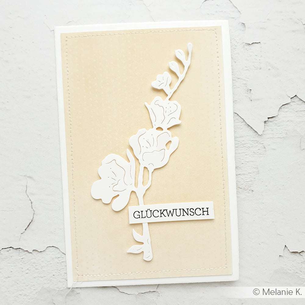 Handgemachte Karte von Alexandra Renke mit einer weißen Blumenstanze mit der Motivstanze Prunk-Kelchblüte und GLÜCKWUNSCH Text auf beigem Strukturpapier. Teil der PAPPcut®ies Kollektion für einzigartige, herzliche Grüße.