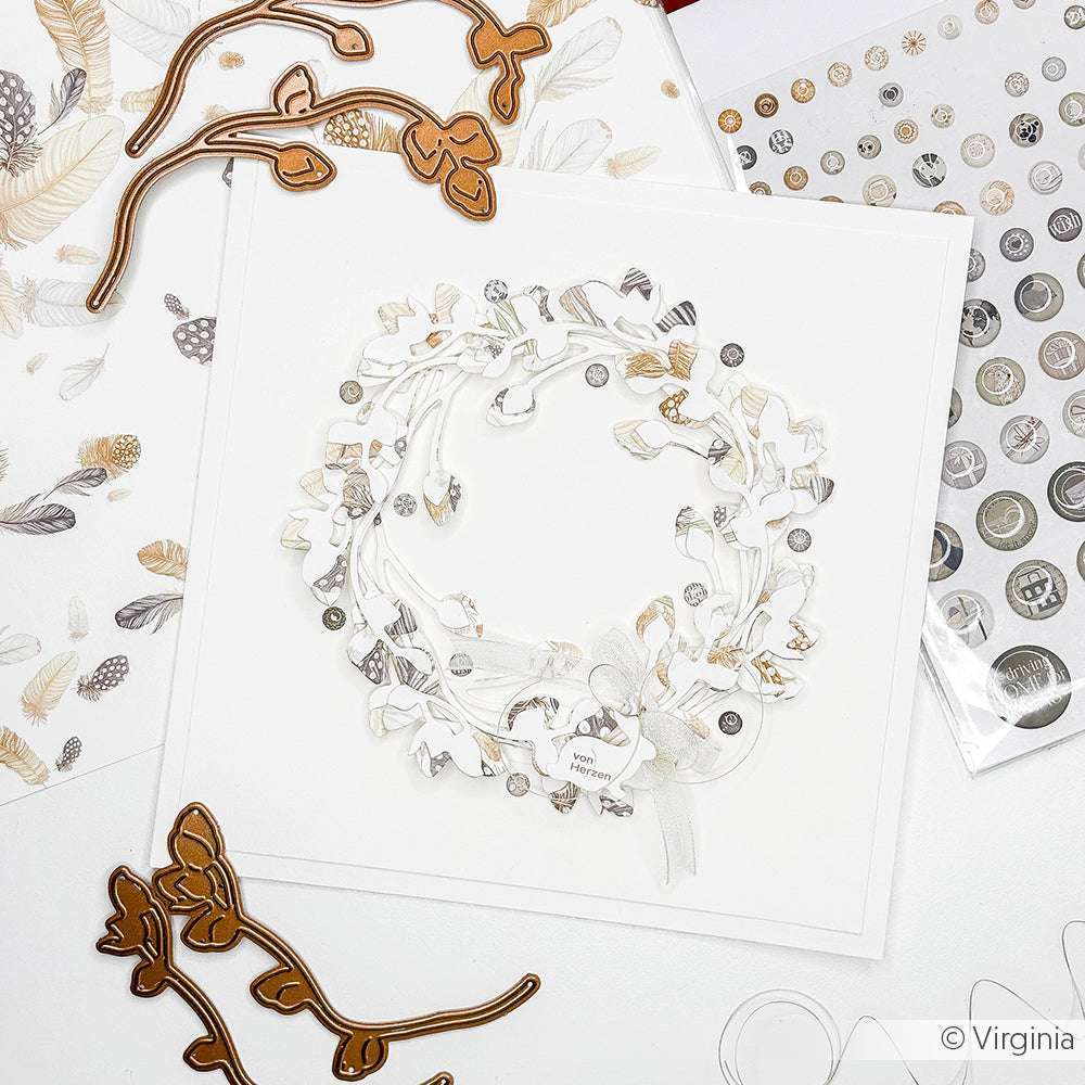 Eine handgefertigte Kranzkarte mit zarten Blattdetails, hergestellt mit Alexandra Renke Deep Edge Motivstanzen und umgeben von PAPPcut®ies Bastelmaterial und Stanzwerkzeugen.