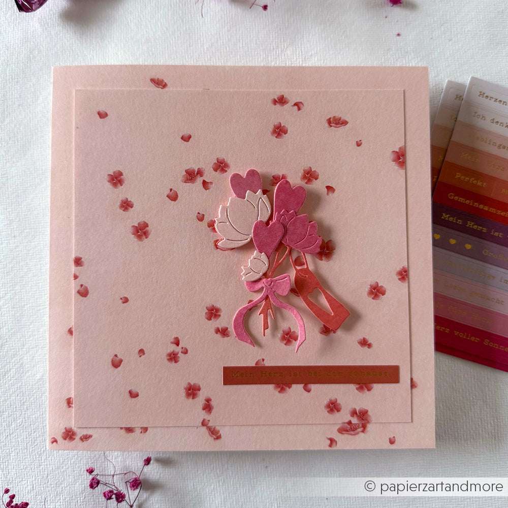 Rosa handgefertigte Karte mit einem Blumenstrauß in Herzform, hergestellt mit Alexandra Renke Motivstanze Blumenstrauß und Deep Edge Motivstanzen, plus deutschem Text, dargestellt auf weißem Hintergrund.