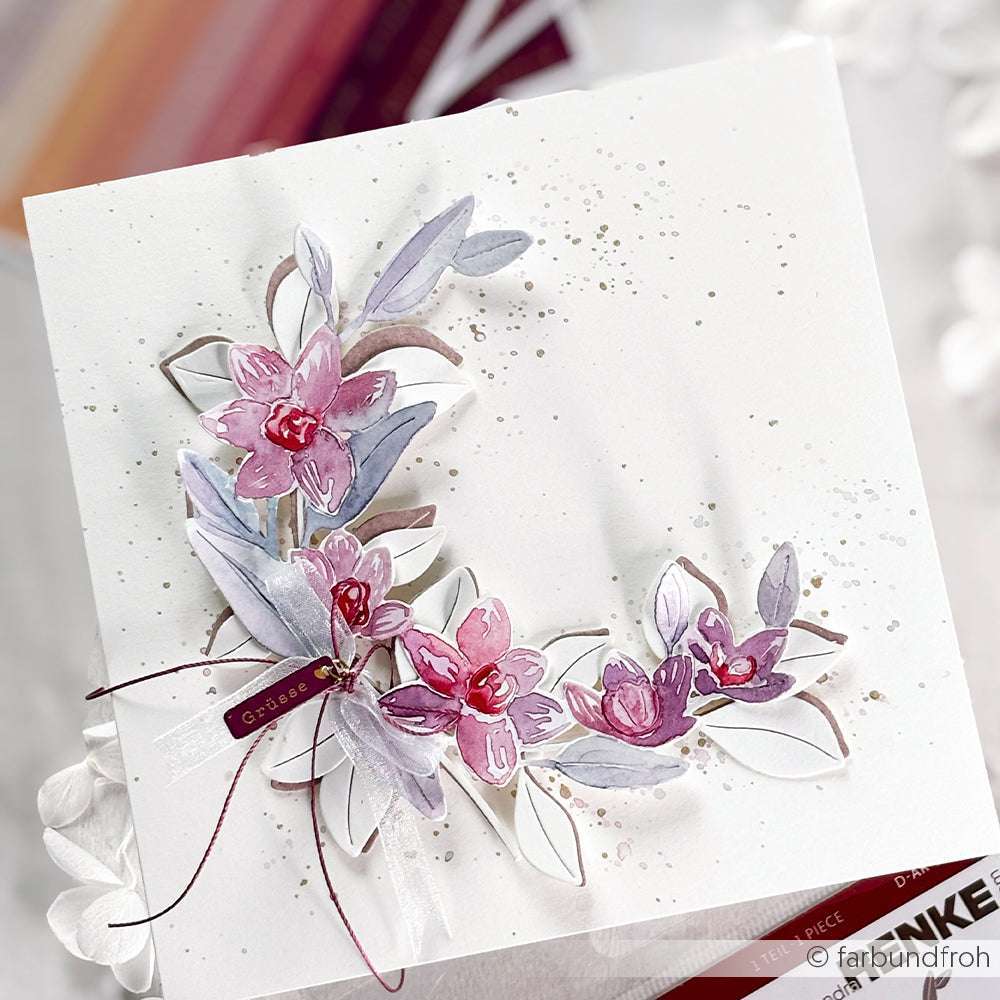 Eine weiße Grußkarte von Alexandra Renke, verziert mit rosa und violetten Aquarellblumen, Blättern und einem burgunderroten Band, weist elegante Details auf, die von PAPPcut®ies und Deep Edge Motivstanzen inspiriert sind.