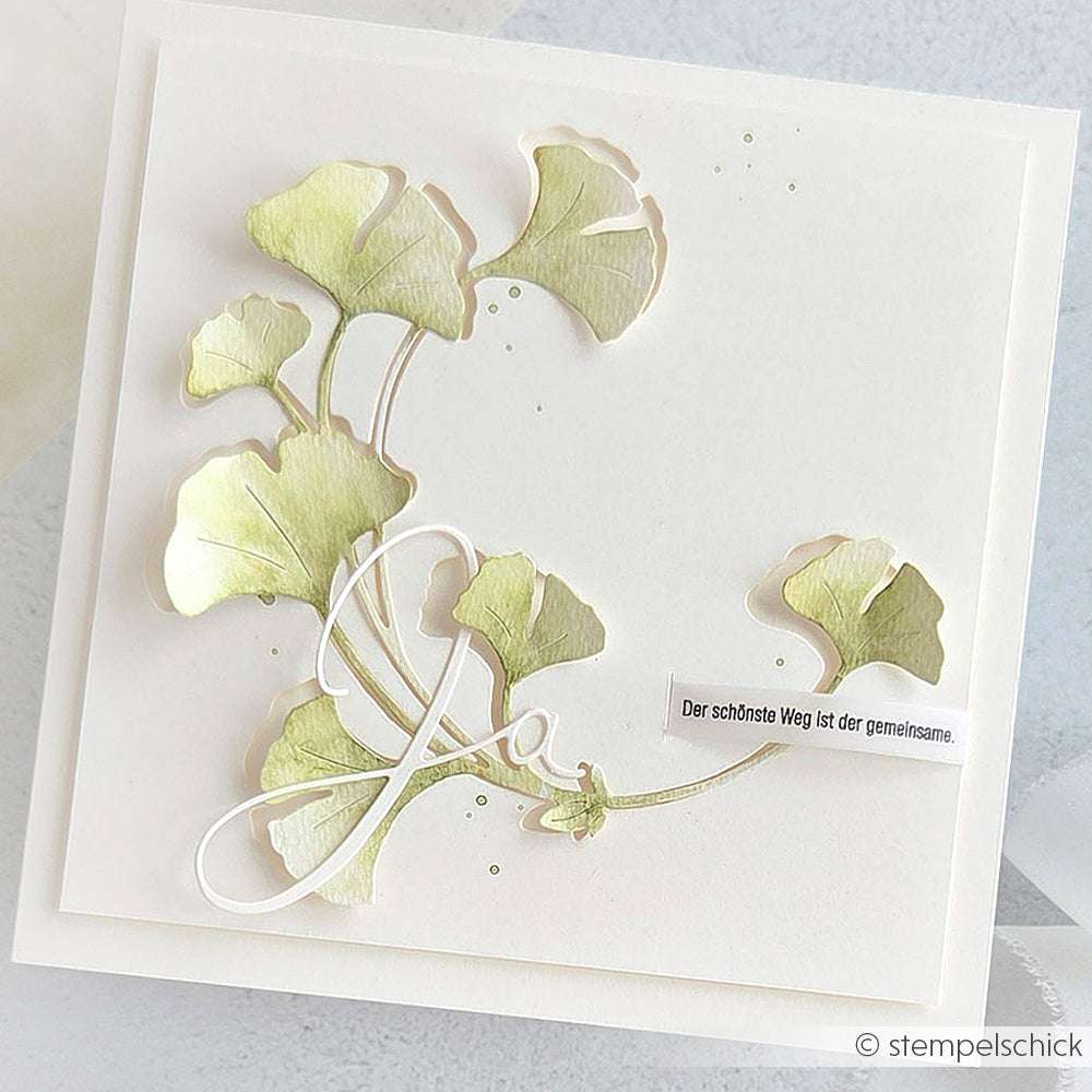Handgefertigte Karte von Alexandra Renke mit grünen Ginkgoblättern, elegantem kursivem "Ja" und deutschem Text auf weißem Grund - hergestellt mit DieCut Systemen für Präzision und mit dem Ginkgo-Kranz Motivstanze Design.