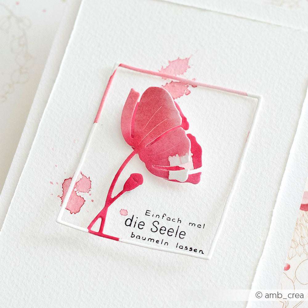 Eine rosafarbene Aquarellblume mit dem deutschen Text "Einfach mal die Seele baumeln lassen", mit zarten Details wie PAPPcuties oder Motivstanze Mohn im Rahmen, auf weißem Papier. Marke: Alexandra Renke.