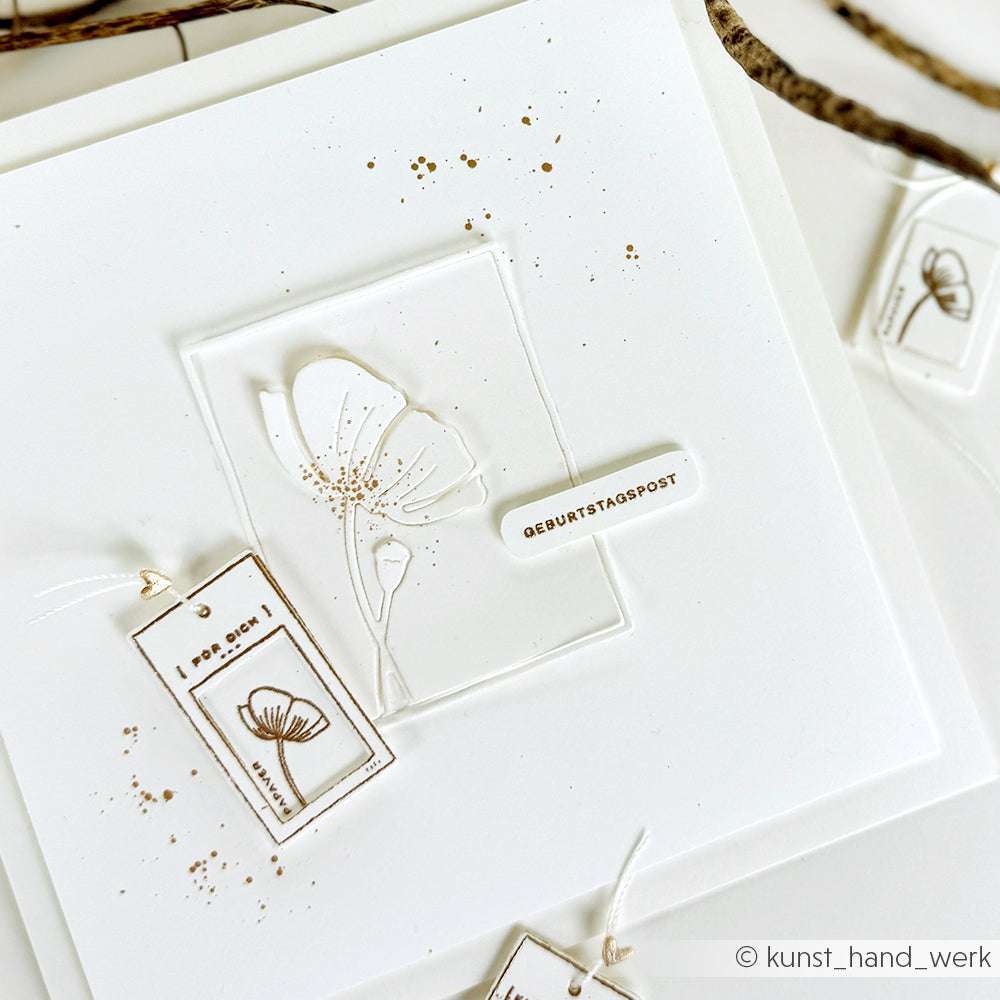 Minimalistische weiße Karte von Alexandra Renke mit zarter Blumenzeichnung, deutschem Text, kleinen goldenen Spritzern und präzisen Details, die mit PAPPcut®ies Deep Edge Motivstanzen hergestellt wurden.