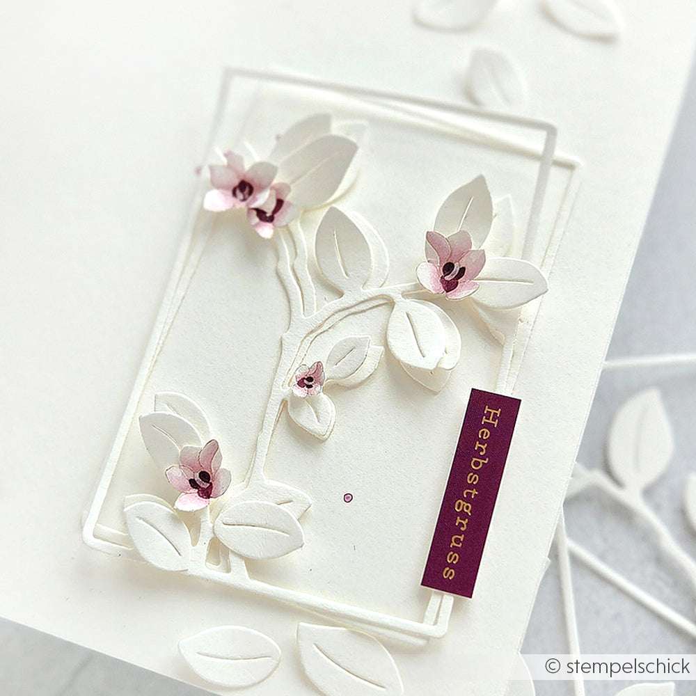 Weiße, geprägte Karte mit zarten Zweigen, Blättern, rosa Blumen und einem lila Herbstgruss-Anhänger, hergestellt mit Alexandra Renke's PAPPcut®ies und Deep Edge Motivstanzen für exquisite Details.