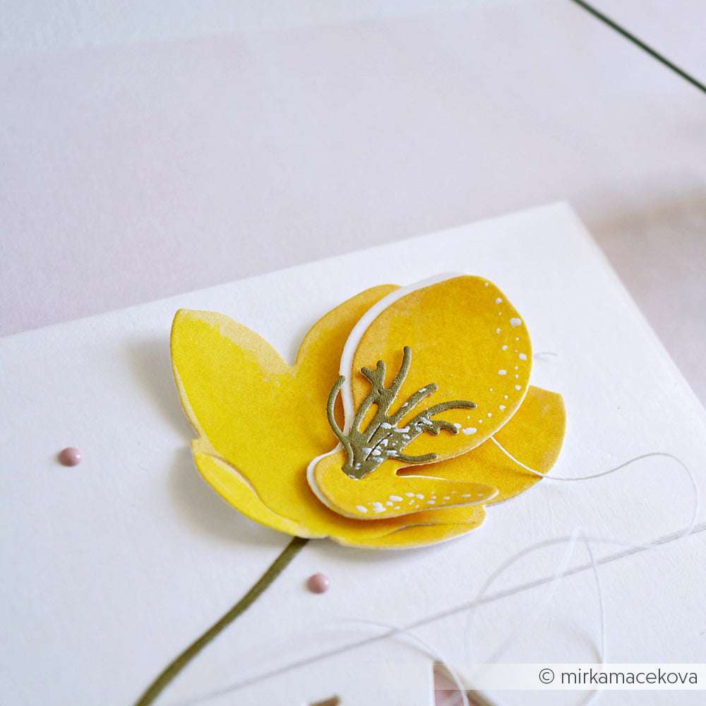 Nahaufnahme einer handgefertigten gelben Papierblume auf weißem Hintergrund, die mit zarten Details und einem grünen Stiel mit Alexandra Renke Deep Edge Motivstanzen für präzise Schnitte gefertigt wurde.