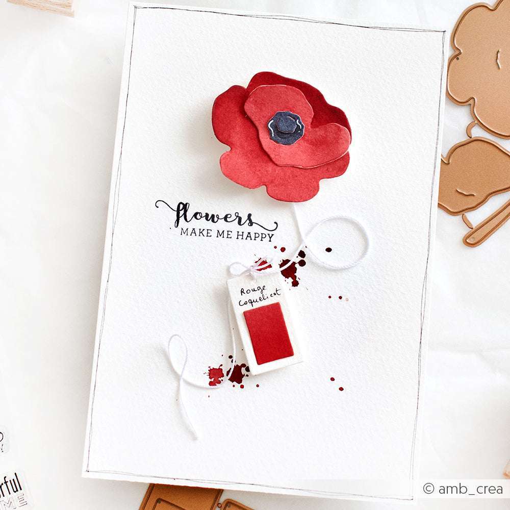 Eine handgefertigte Karte von Alexandra Renke zeigt eine rote Papierblume, die mit Deep Edge Stanzen hergestellt wurde, und ein "rouge coquelicot"-Anhänger mit dem Spruch "Blumen machen mich glücklich".