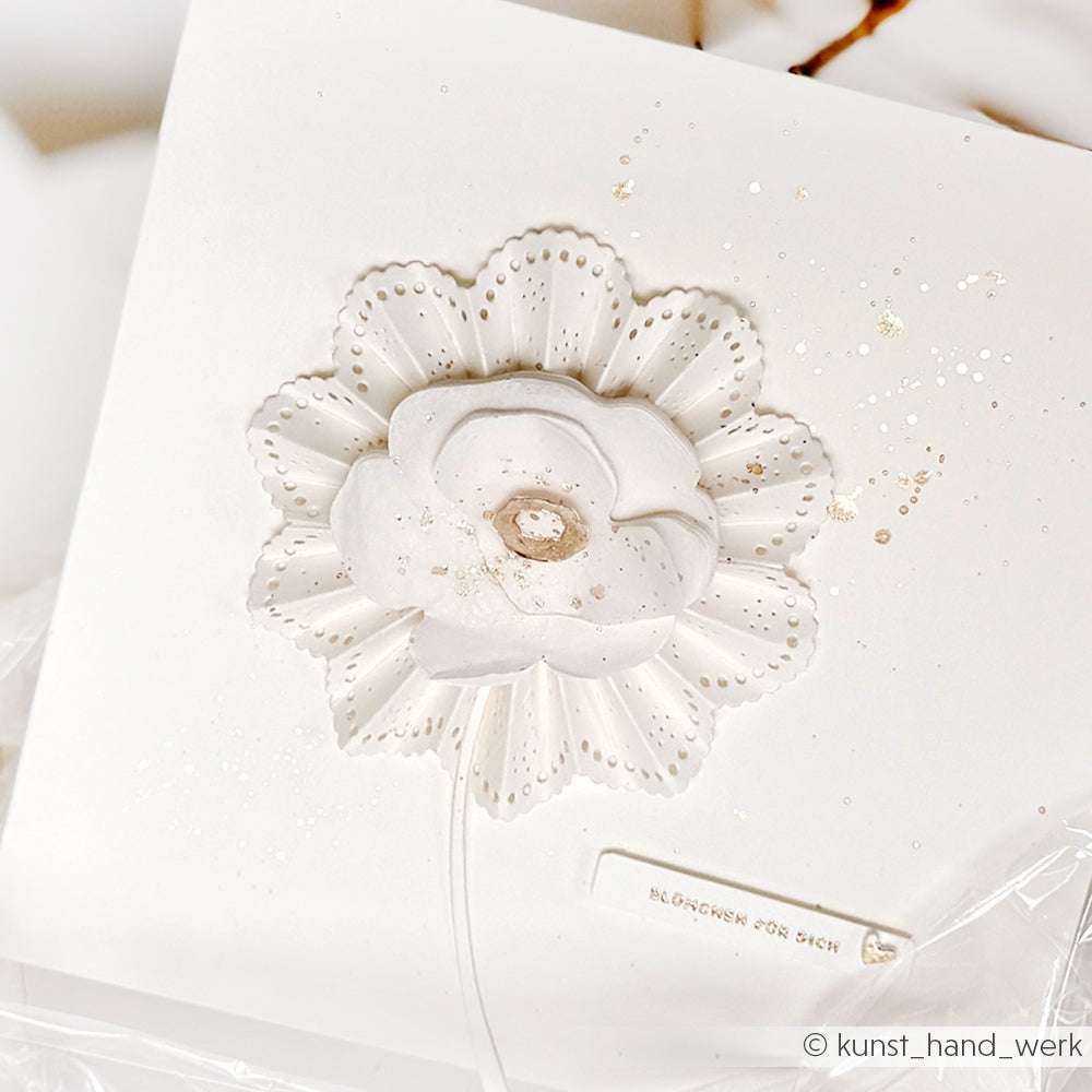 Weißer geprägter Blumendekor auf einer quadratischen weißen Karte, hergestellt mit Alexandra Renke Deep Edge Motivstanzen, mit zarten Details und kleinen Goldspritzern für ein raffiniertes Finish.