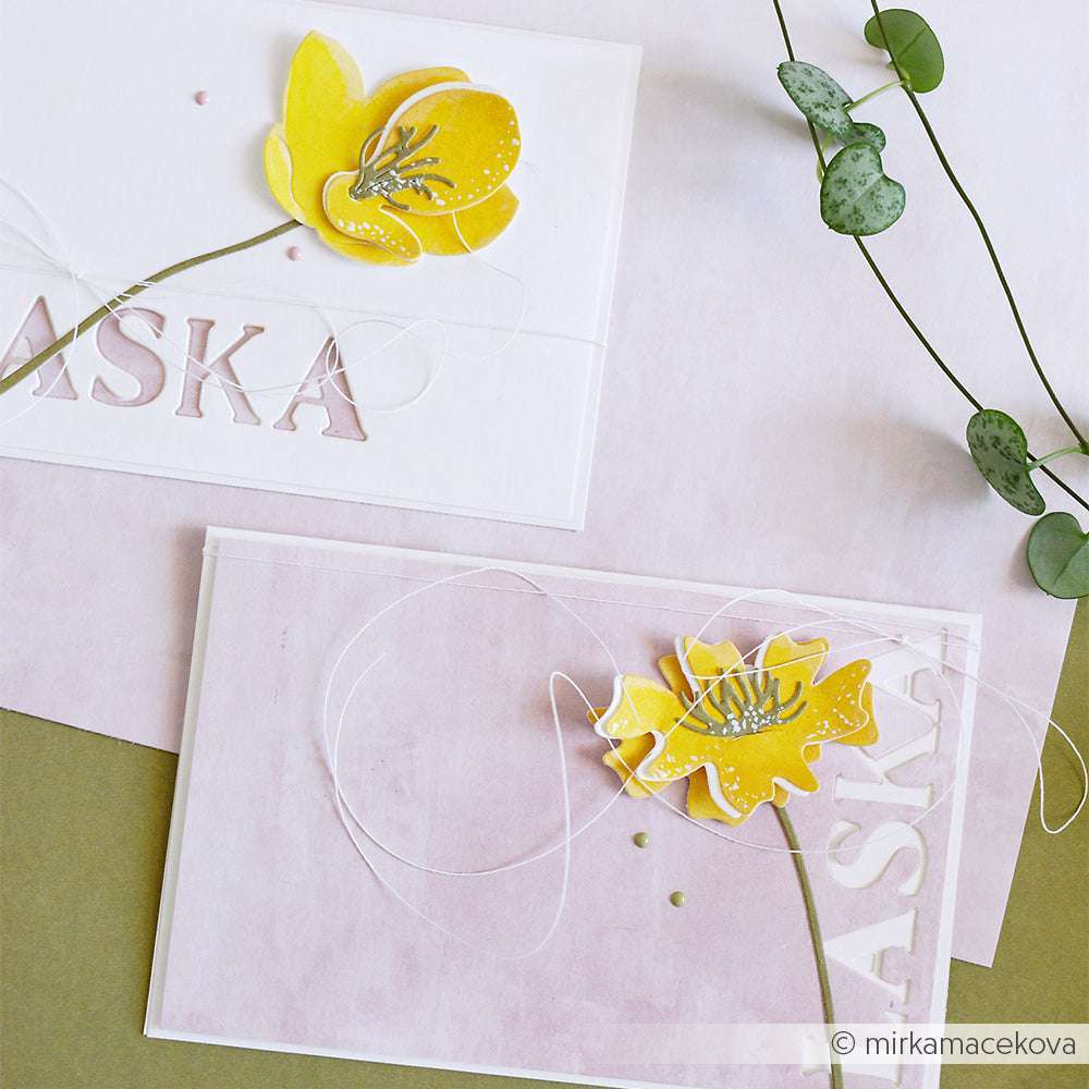 Zwei Grußkarten mit gelben Papierblumen, Schnur und ausgeschnittenen Buchstaben - hergestellt mit Alexandra Renke Deep Edge Motivstanzen - liegen auf einem pastellrosa und weißen Hintergrund.