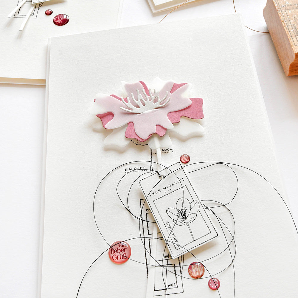 Eine rosafarbene und weiße Papierblume schmückt eine künstlerische Karte mit wirbelnden schwarzen Linien und roten Akzenten, die mit Alexandra Renke Deep Edge Stanzen für präzise Details gefertigt wurde.
