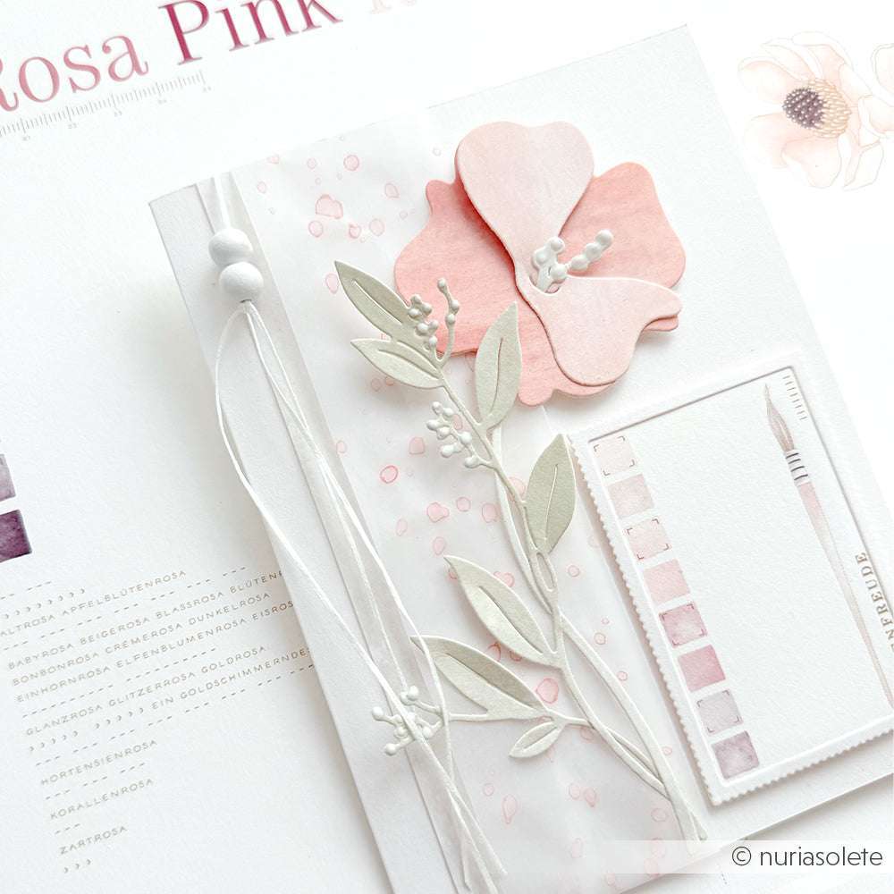 Eine zarte Blumenkarte mit rosafarbenen Blüten, Blättern, einem Farbmuster und weißer Schnur auf hellem Hintergrund - gestaltet mit der Motivstanze Geschwungene Formblüte von Alexandra Renke für eine elegante Note.
