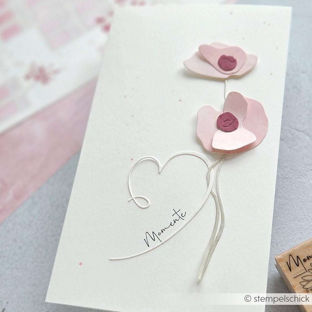 Handgemachte Karte von Alexandra Renke mit zwei rosafarbenen Papierblumen, einer Herzkontur und "Momente" in eleganter Schrift, hergestellt mit Deep Edge Stanzen für Details und PAPPcut®ies Motivstanze für zusätzlichen Charme.