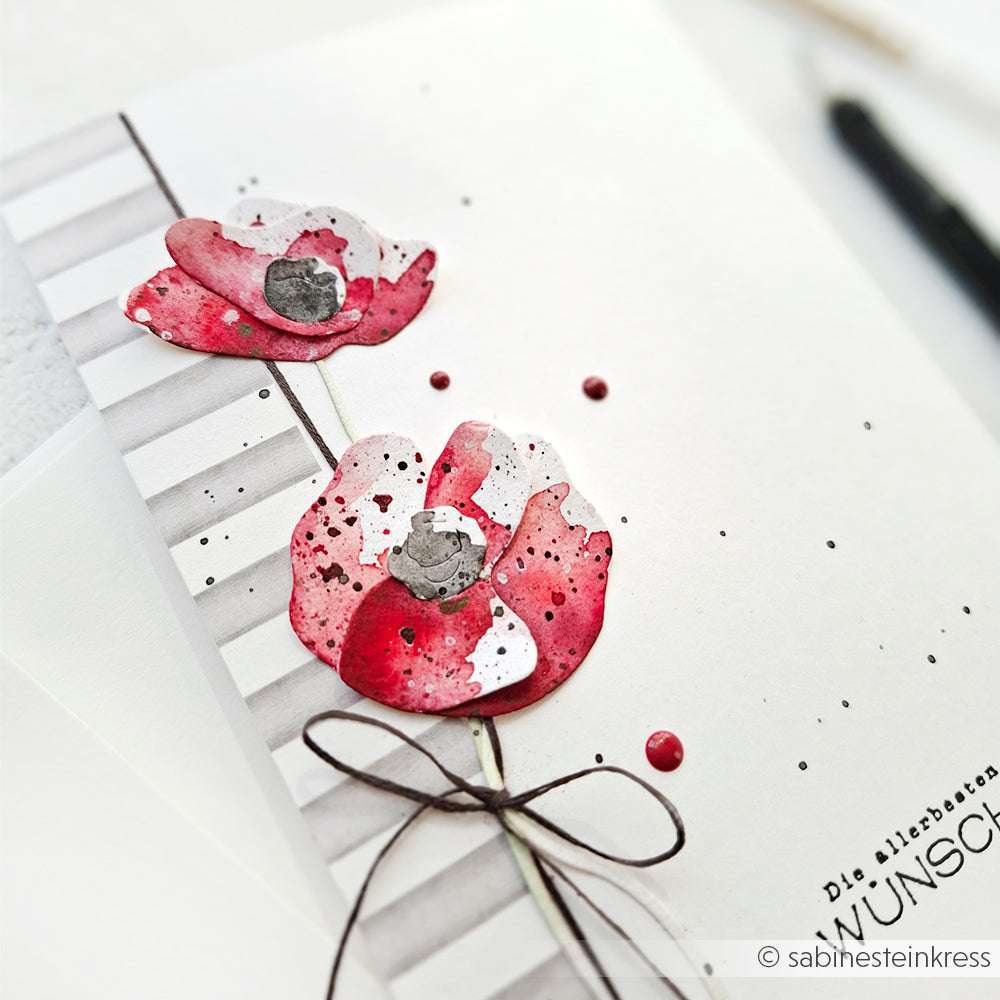 Grußkarte von Alexandra Renke mit zwei roten Mohnblumen, einer braunen Schnurschleife und einem gestreiften, gesprenkelten weißen Hintergrund - ideal, um Ihre Lieblingskreationen auszustellen oder mit Deep Edge Stanzen Motivstanze Designs zu kombinieren.