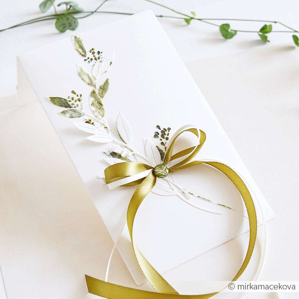 Elegante weiße Karte von Alexandra Renke mit geprägten Blättern und einem grünen Satinband, hergestellt mit Deep Edge Stanzen für präzise Details, dargestellt auf einem hellen Hintergrund.