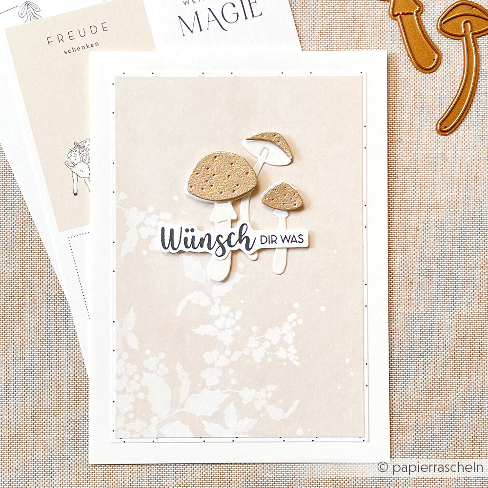 Eine Grußkarte von Alexandra Renke mit drei illustrierten Pilzen (Motivstanze Glückspilze-Trio 2) und dem deutschen Text "Wünsch dir was" auf beigem Hintergrund - ideal für Fans von DieCut Systemen und Stanzen für Basteln.