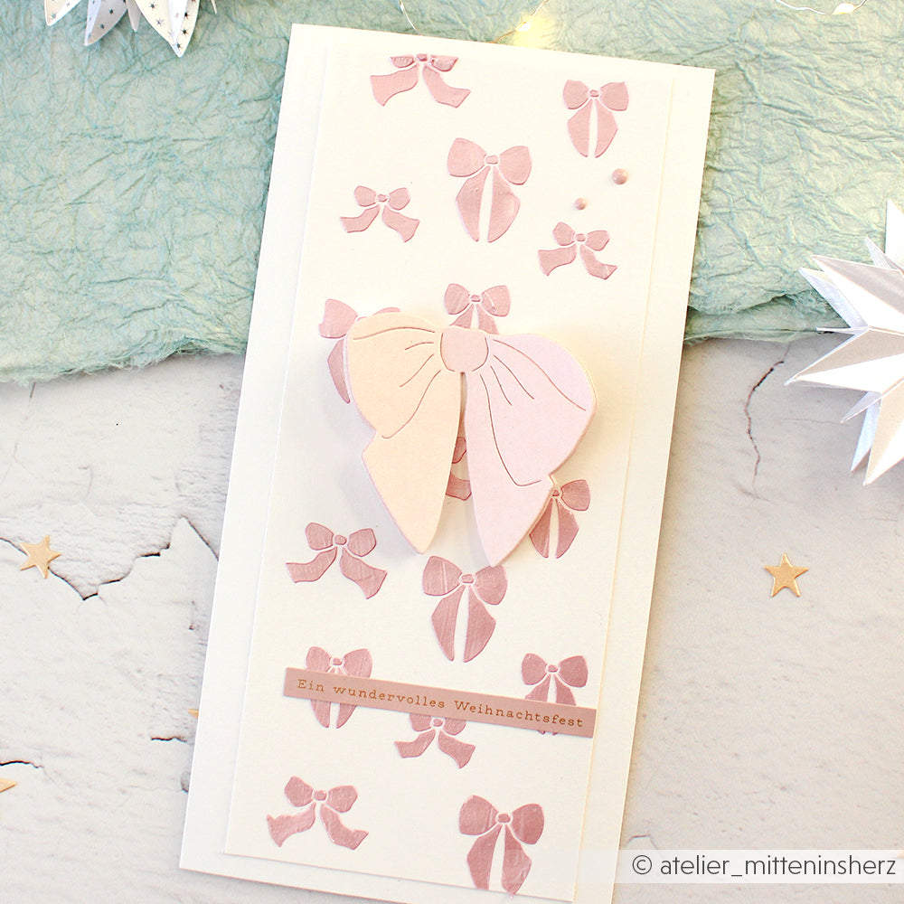 Eine handgefertigte Karte von Alexandra Renke, hergestellt mit Designpapieren und DieCut Systemen, mit rosa Schleifen, einer großen 3D-Schleife und dem deutschen Text "Ein wundervolles Weihnachten" für einen festlichen Touch.