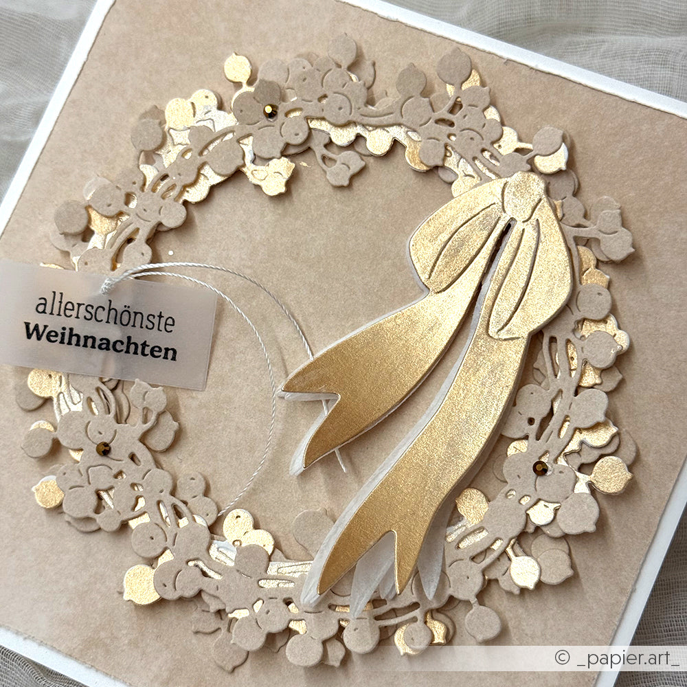 Handgefertigte beige-goldene Weihnachtskranzkarte von Alexandra Renke, hergestellt mit hochwertigen Designpapieren, mit goldener Schleife, Weihnachtsgrußanhänger und eleganten festlichen Details.