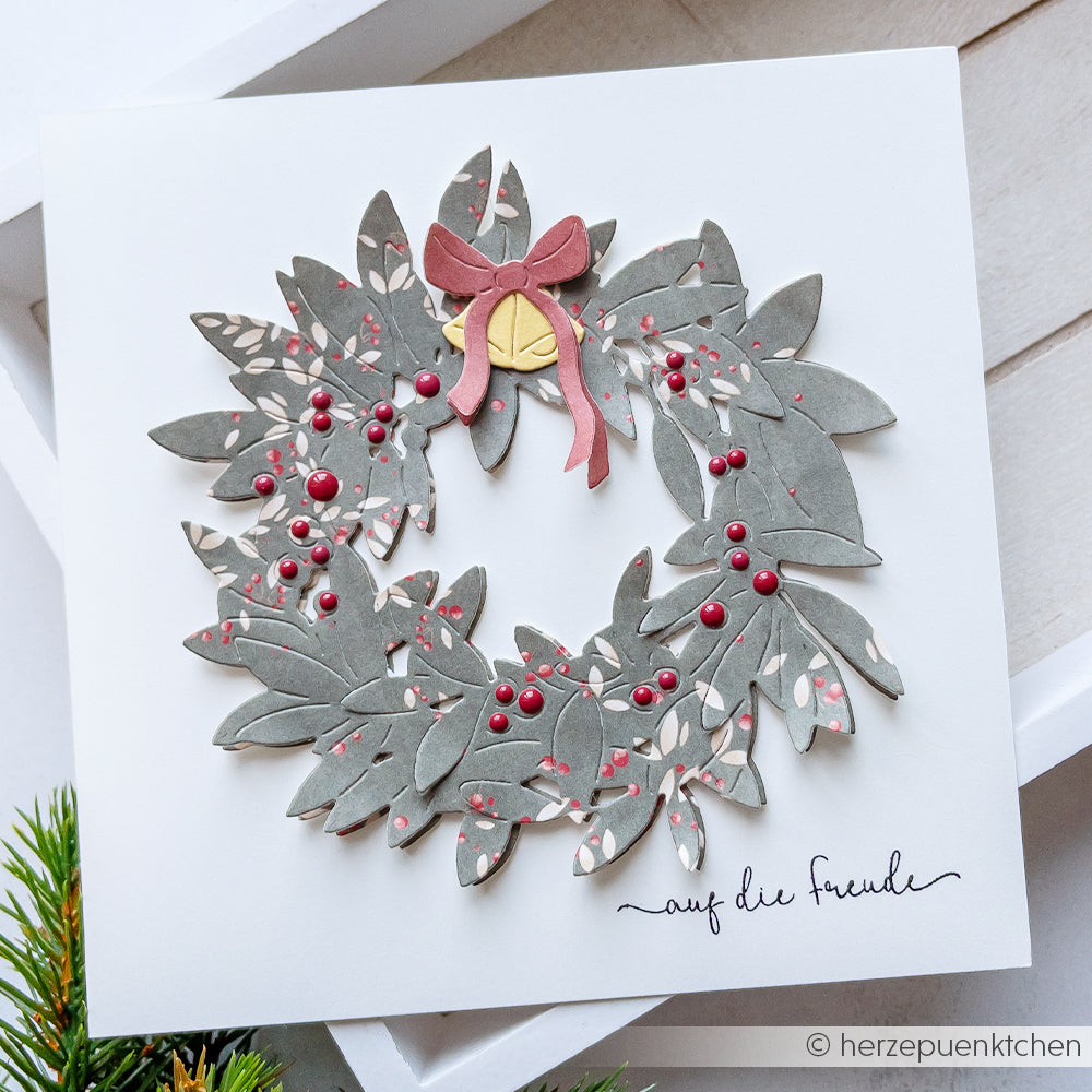 Eine handgeschöpfte Papierkranzkarte von Alexandra Renke, gefertigt mit Motivstanze Blätterkranz und Designpapieren, verziert mit roten Beeren, einer Schleife und dem Text "auf die freude".