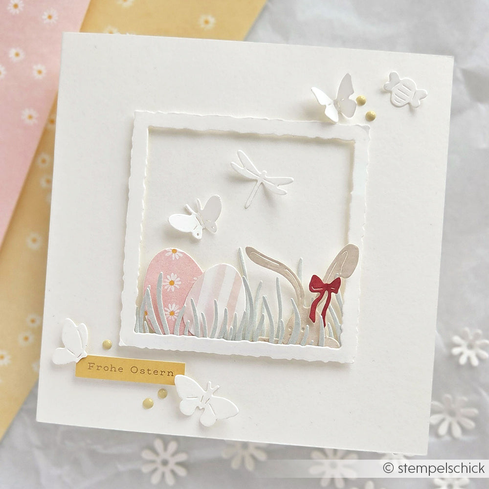 Handgefertigte Osterkarte von Alexandra Renke mit pastellfarbenen Eiern, Gras, Schmetterlingen und einer Libelle, hergestellt mit dem Motivstanze Grasbüschel-Set und bunten Designpapieren. Enthält den Text "Frohe Ostern.