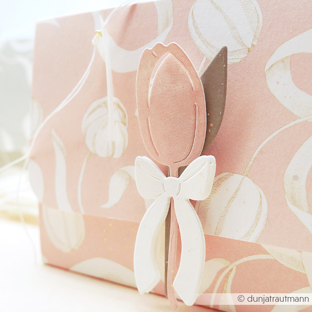 Rosa geblümter Umschlag mit einer Tulpe und einer weißen Schleife in der Mitte, gefertigt mit Alexandra Renke Motivstanze Tulpensträußchen und eleganten Designpapieren für ein charmantes Finish.