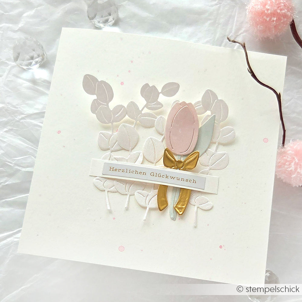 Handgefertigte Alexandra Renke Karte mit pastellrosa Blume, goldener Schleife, weißen Blättern und "Herzlichen Glückwunsch"-Text auf der Vorderseite, hergestellt mit Stanzsystemen und Motivstanze Tulpensträußchen für einzigartige Details.