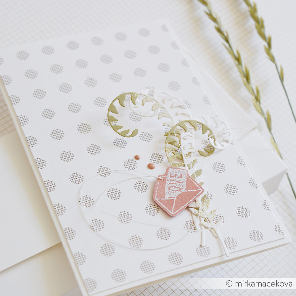 Eine handgefertigte Karte mit einem Polka-Dot-Muster, aus Papier geformte Blätter, die mit einer Motivstanze „Farn Paar“ ausgestanzt wurden, und ein rosa Herz mit der Aufschrift „LOVE“, gefertigt aus hochwertigen Designpapieren.