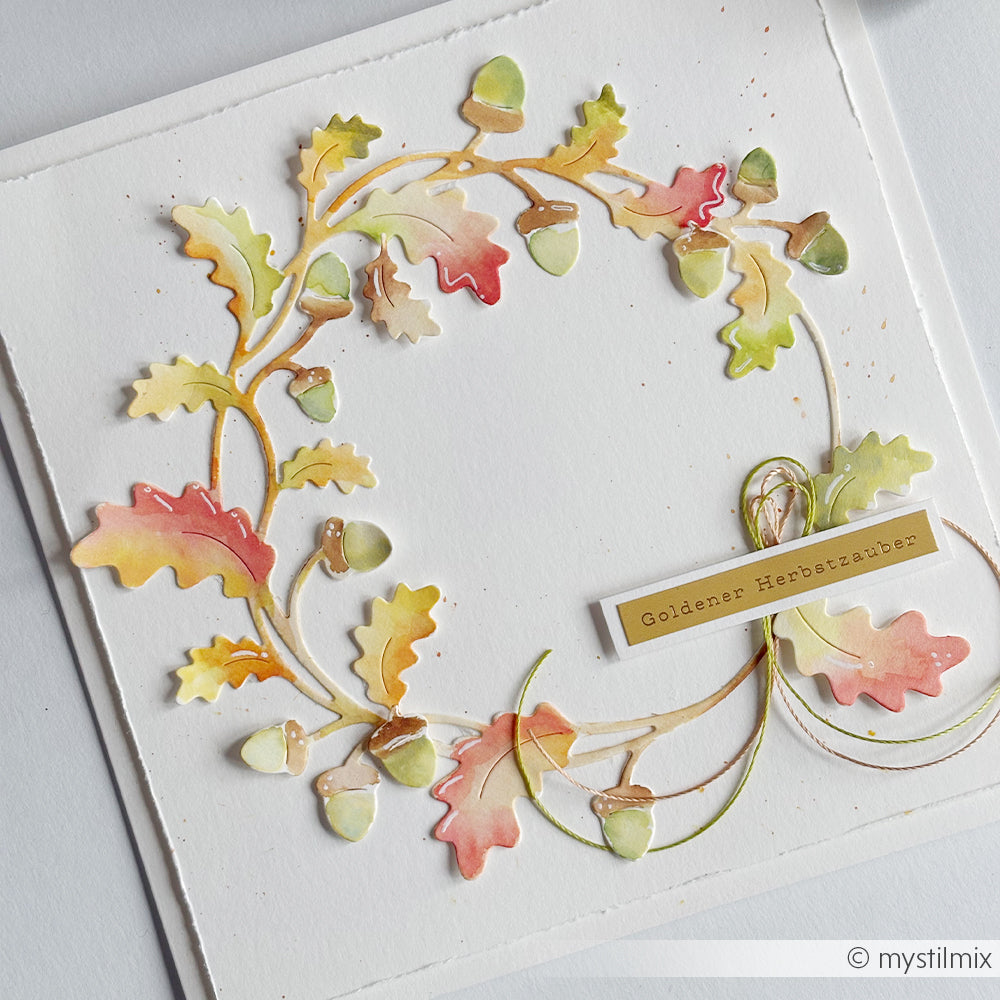 Handgefertigte Herbstkranz-Karte mit bunten Blättern, Eicheln und einem „Goldener Herbstzauber“-Etikett, gestaltet mit einer Motivstanze „Eichenkranz“ und Stanzen für Designpapier für filigrane Details.
