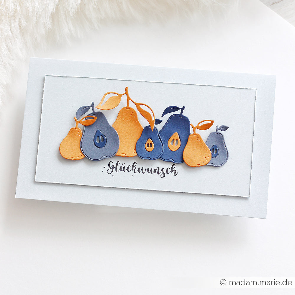 Grußkarte mit blauen und orangefarbenen Birnen, gestaltet mit Designpapieren und hervorgehoben durch den „Glückwunsch“-Schriftzug auf weißem Hintergrund. Das verspielte Motiv wurde mit der Motivstanze „Offene Birnen“ gestaltet und verleiht der Karte eine einzigartige und charmante Note.