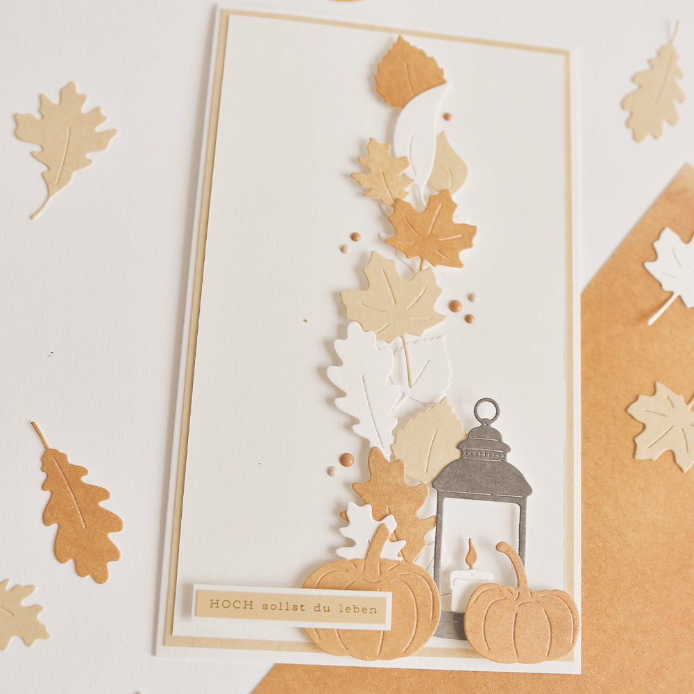 Handgefertigte Karte mit mehrschichtigen Herbstblättern, hergestellt mit der Motivstanze „Herbstlaub“ und hochwertigen Designpapieren, verziert mit einer Laterne, Kürbissen und dem deutschen Text: „HOCH sollst du leben“.