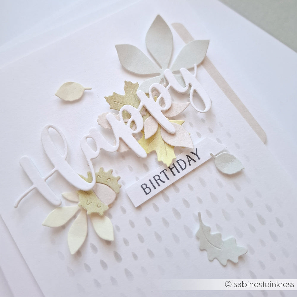 Handgefertigte Karte mit „Happy Birthday“-Schriftzug und pastellfarbenen Papierblättern, gestaltet mit Designpapieren und der Motivstanze „Blätterwirbel“, auf weißem, strukturiertem Hintergrund.