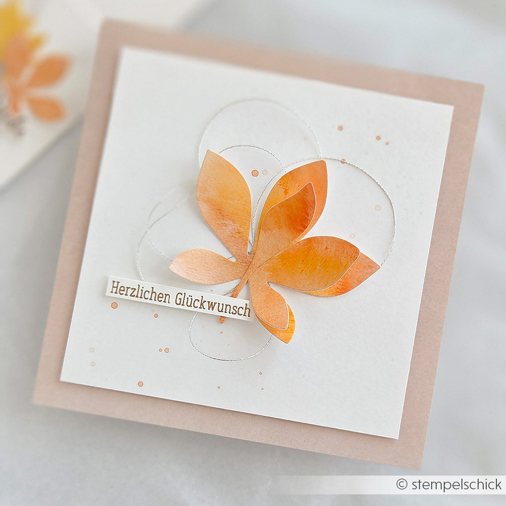 Quadratische Karte mit einem orangefarbenen Schmetterling und dem Schriftzug „Herzlichen Glückwunsch“ auf weißem Hintergrund, verziert mit zarten Details aus Designpapier.