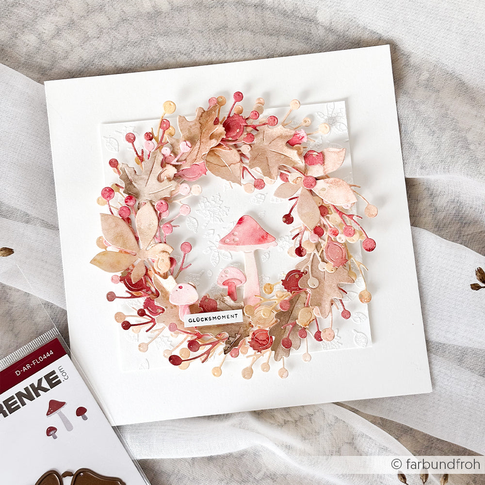 Handgefertigte Karte aus Designpapieren mit einem rosa-braunen Papierkranz, der durch Pilze und Beeren auf weißem Hintergrund akzentuiert wird. Die filigranen Details werden mithilfe der Motivstanze „Kleines Pilz-Trio“ und Stanzsystemen für präzise Schnitte hervorgehoben.