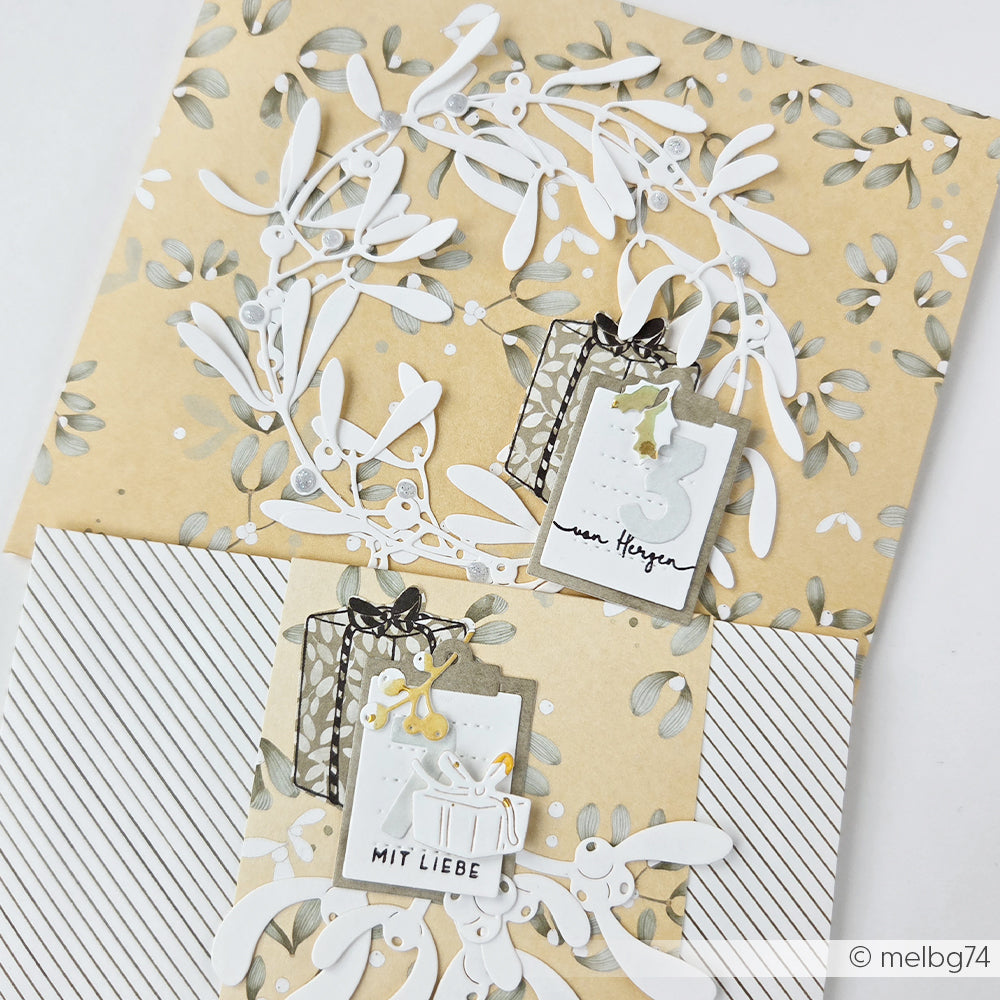 Zwei handgefertigte Karten mit Mistelzweigen, Geschenkanhängern und deutschen Texten, hergestellt aus Designpapieren.