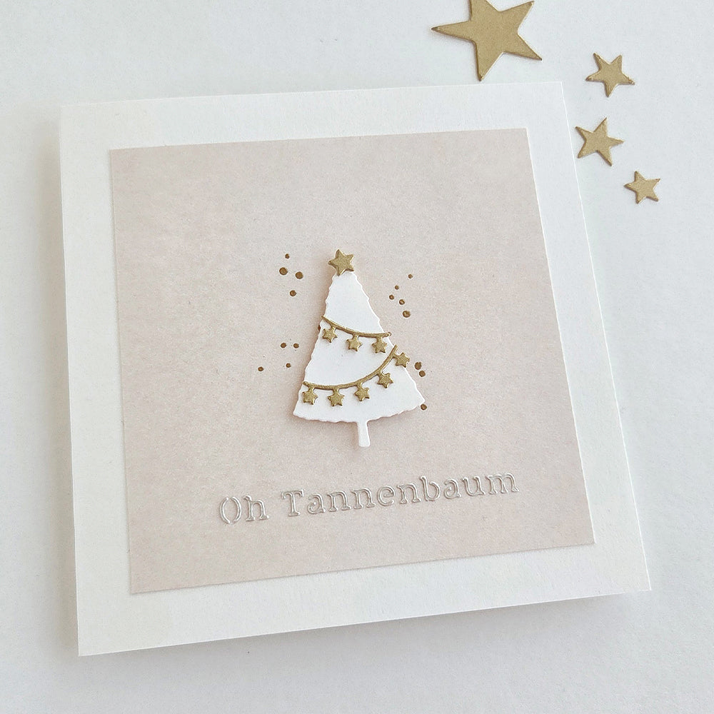 Weihnachtskarte mit einem weißen Papierbaum, gestaltet mit der Motivstanze „Kleine Tannen“, verziert mit goldenen Sternen und dem Text „Oh Tannenbaum“.