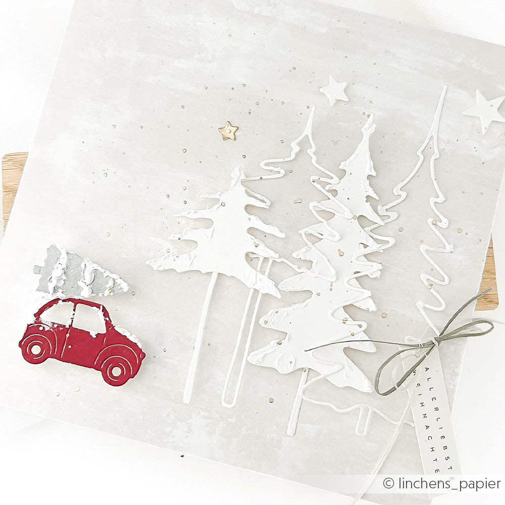 Ein rotes Spielzeugauto transportiert einen winzigen Weihnachtsbaum in der Nähe von Outline Schleifentannen und Stern-Ausschnitten aus Papier.