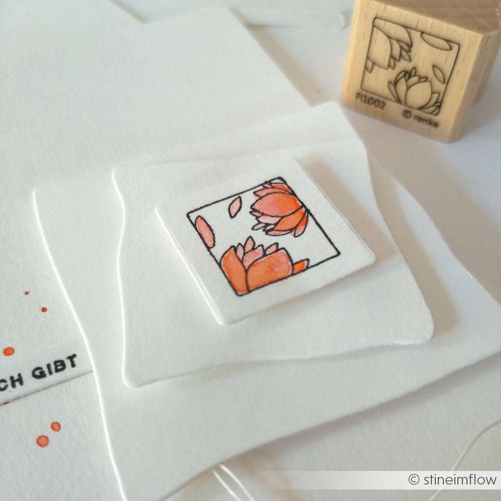 Der Stempelgummi von Alexandra Renke mit seinem orangefarbenen Blütenornament Outline setzt einen lebendigen Akzent auf weißem Papier.