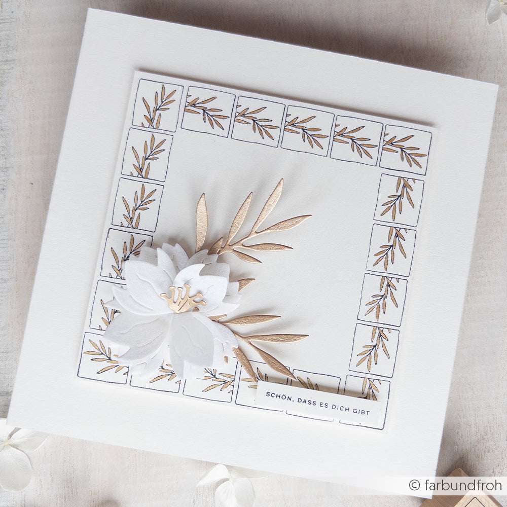 Quadratische weiße Karte von Alexandra Renke mit goldenen Blättern, einer weißen Blume und einem Rand aus Blatt- und Gräserornamenten; mit deutschem Text am unteren Rand.