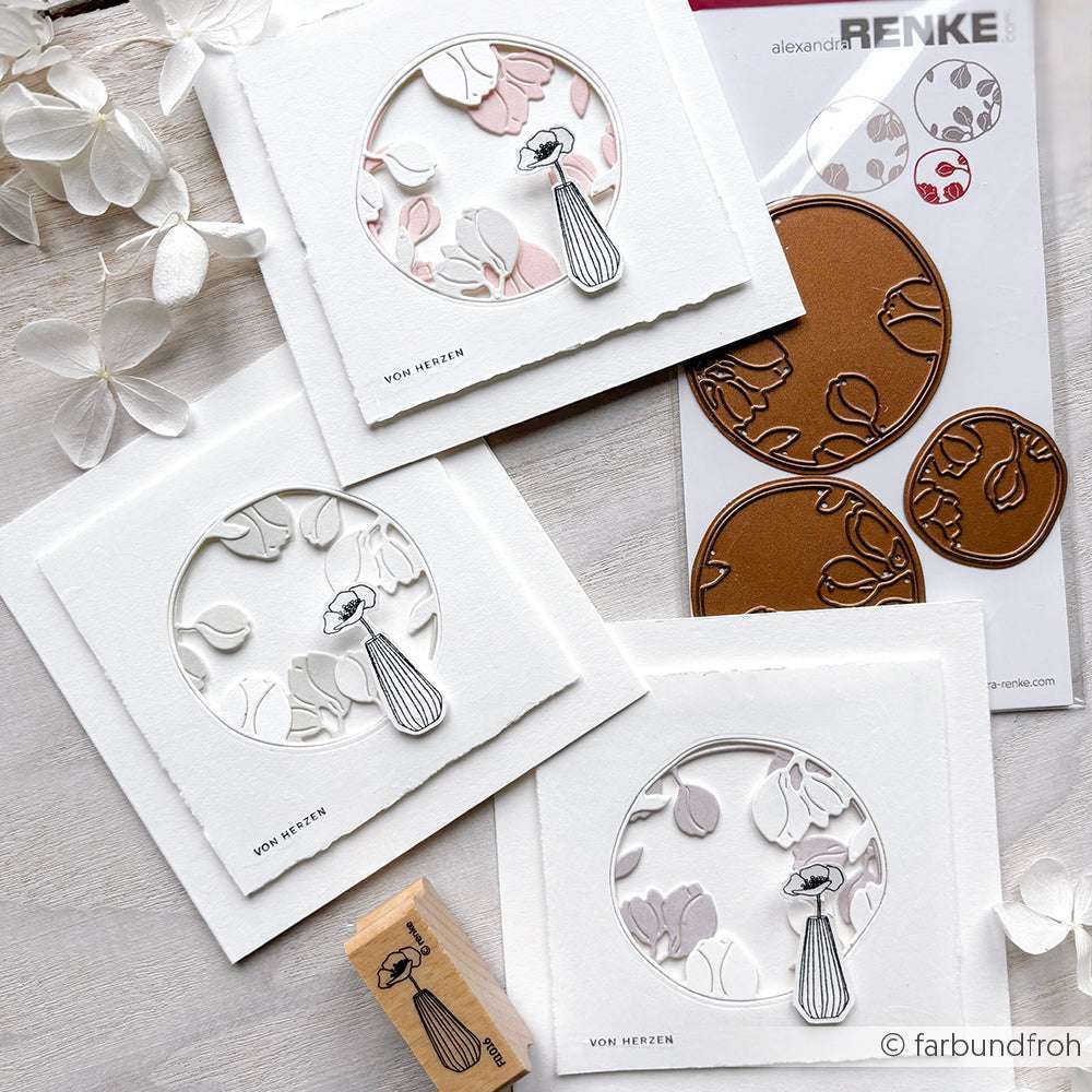 Drei handgefertigte Karten von Alexandra Renke mit geprägten Blumenmustern, einem Frauenstempel, Stanzungen und einem Stempel aus Holz, die auf einer weißen Fläche präsentiert werden.