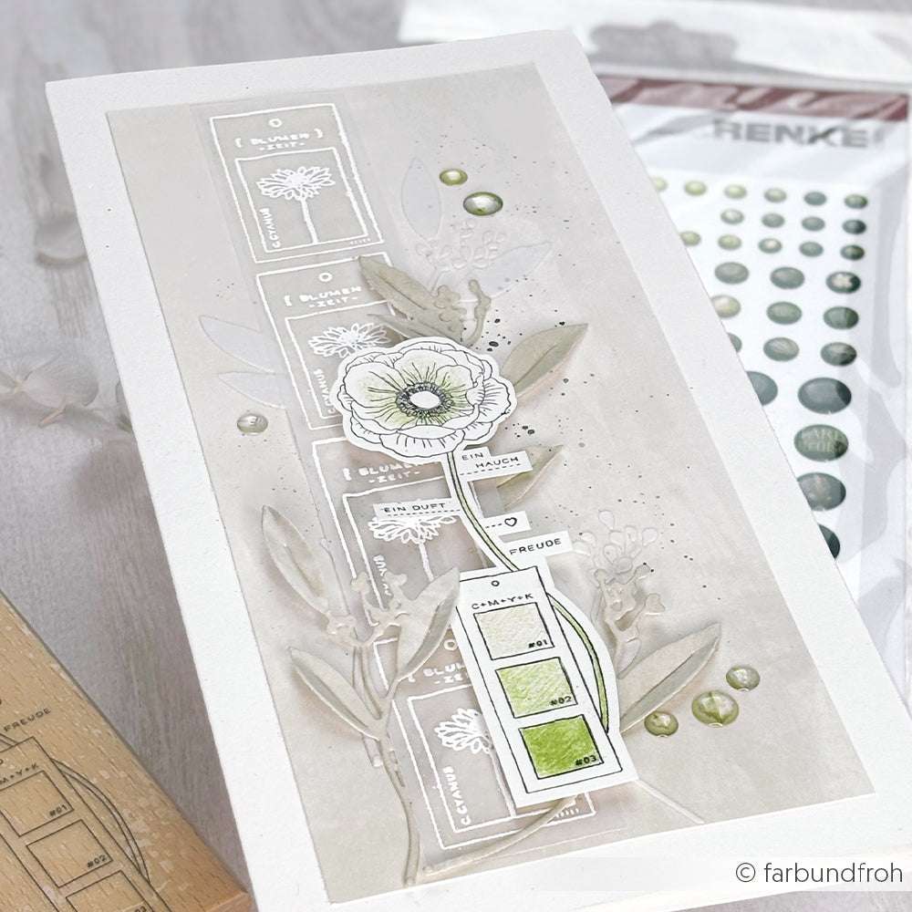 Handgemachte Karte von Alexandra Renke mit botanischen Motiven, geschichteten Rechtecken, einer mit dem Kornblume Stempel gestempelten Blume und grünen Verzierungen auf weißem Hintergrund.