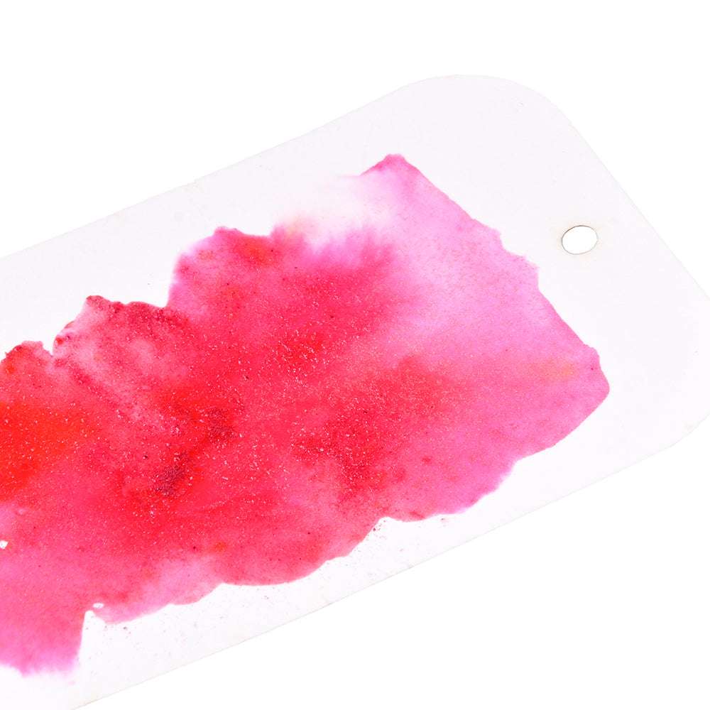 Ein weißer Anhänger mit einem Loch und leuchtend roten und rosa Aquarellspritzern von Lindy's Stamp Gang, perfekt für Papierprojekte oder zum Experimentieren mit magischen Farbmischungen mit Puder.