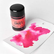Ein Lindy's Stamp Gang Magical Shaker mit Magical Powder sowie ein Anhänger mit einer leuchtend rosa Aquarellfarbe - ideal zum Mischen von Farben in Ihren Papierprojekten.