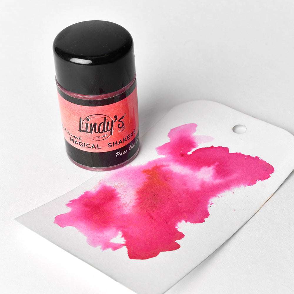 Ein Lindy's Stamp Gang Magical Shaker mit Magical Powder sowie ein Anhänger mit einer leuchtend rosa Aquarellfarbe - ideal zum Mischen von Farben in Ihren Papierprojekten.