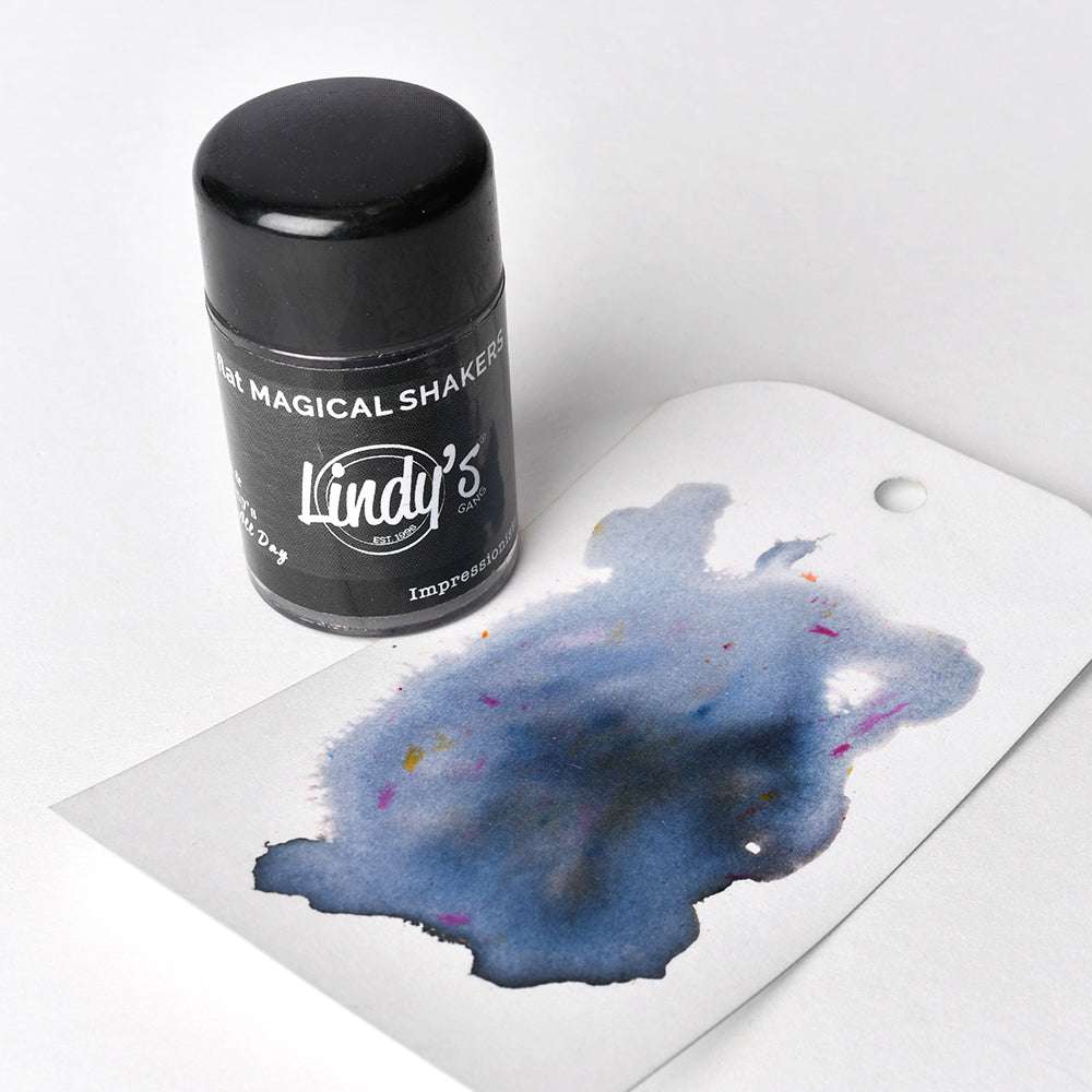 Ein schwarzes Lindy's Stamp Gang Magical Shaker-Fläschchen, gefüllt mit High-Pigment-Pulver, steht neben einem Anhänger, der mit blauen und violetten Farbspritzern in Aquarelltinte verziert ist.