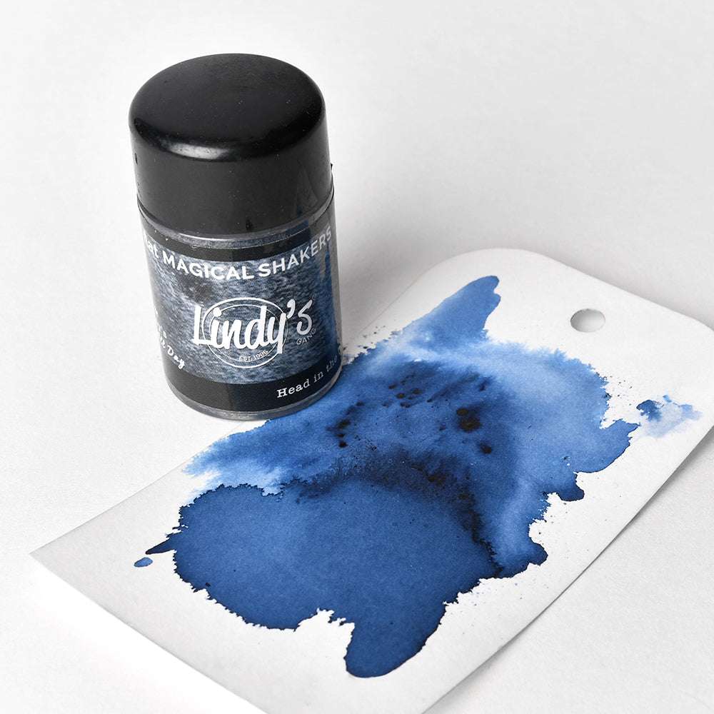Eine Flasche Lindy's Stamp Gang Magical Shakers, gefüllt mit hochpigmentiertem Pulver, mit einem Anhänger mit einem großen blauen Tintenfleck auf weißem Hintergrund.