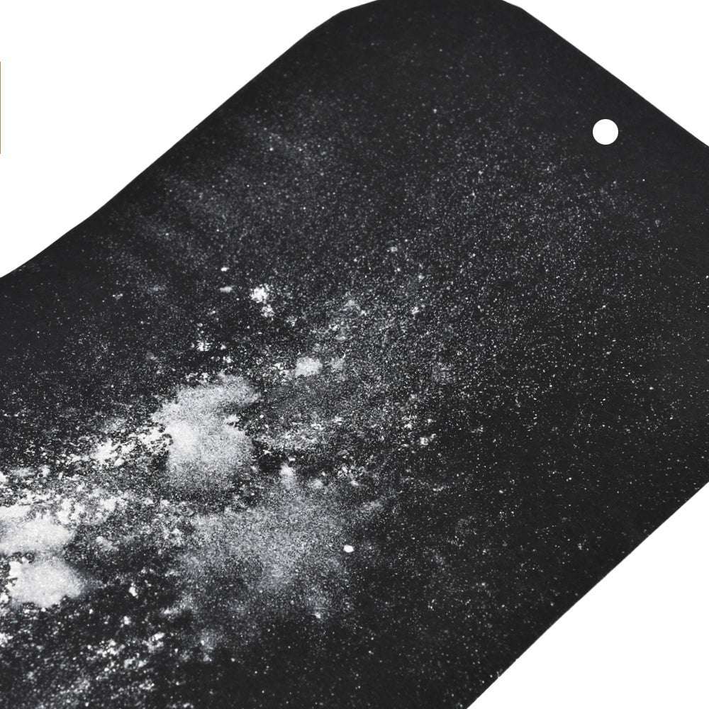 Das weiße, hochpigmentierte Pulver von Lindy's Stamp Gang, das auf eine schwarze Fläche mit einem kleinen Loch oben rechts gestreut wird, erzeugt in diesem Bild auffallend matte Effekte.